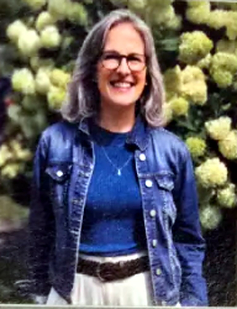 Jessica Fox outdoors in a denim jacket, smiling in front of flowering hydrangeas.